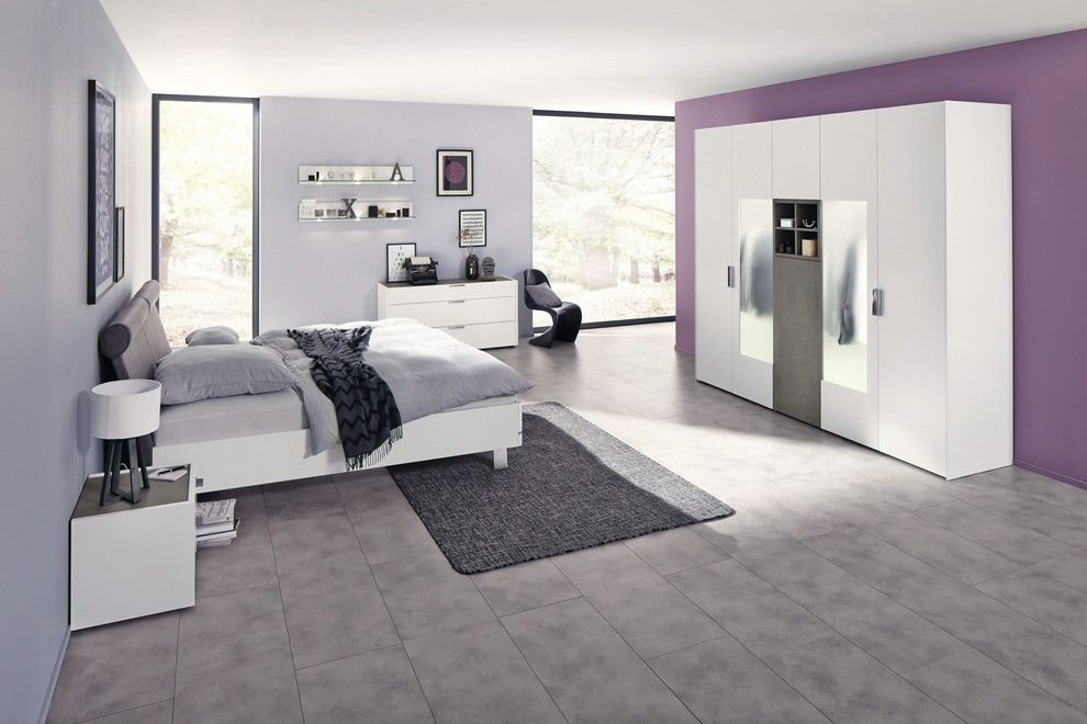 Modelo de dormitorio contemporáneo grande sin chimenea con paredes púrpuras, suelo laminado y suelo gris