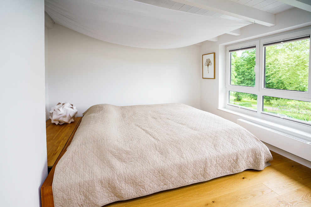 Mittelgroßes Modernes Hauptschlafzimmer ohne Kamin mit weißer Wandfarbe, braunem Holzboden und braunem Boden in Frankfurt am Main
