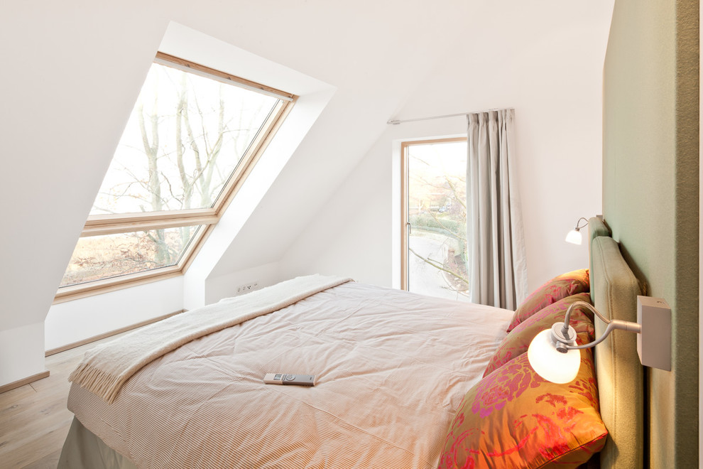 Kleines Modernes Schlafzimmer ohne Kamin mit weißer Wandfarbe und braunem Holzboden in Hamburg
