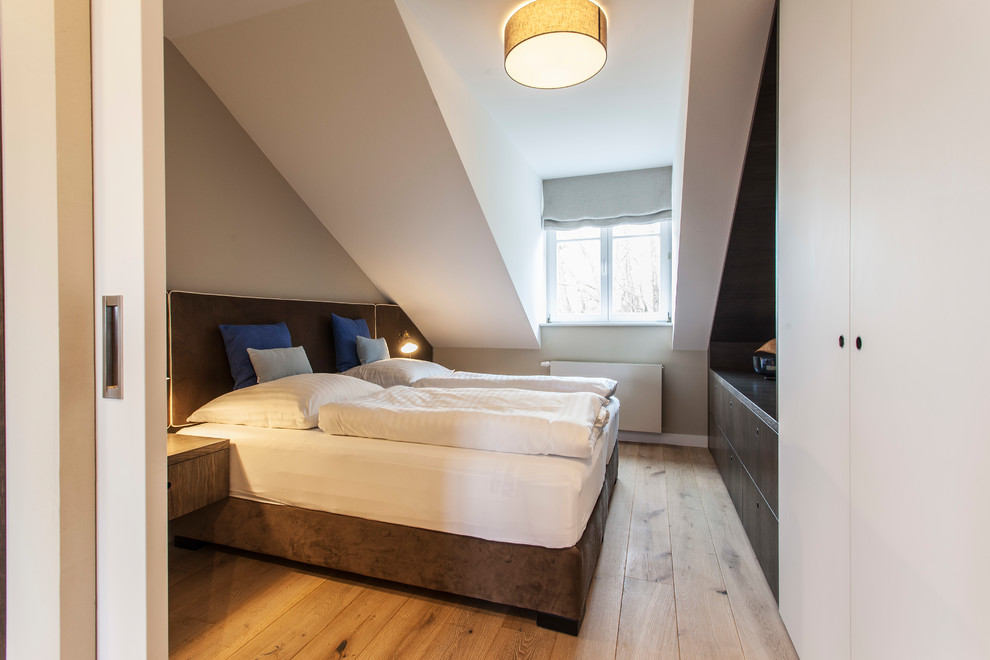 Modernes Schlafzimmer mit weißer Wandfarbe, braunem Holzboden und braunem Boden in Berlin