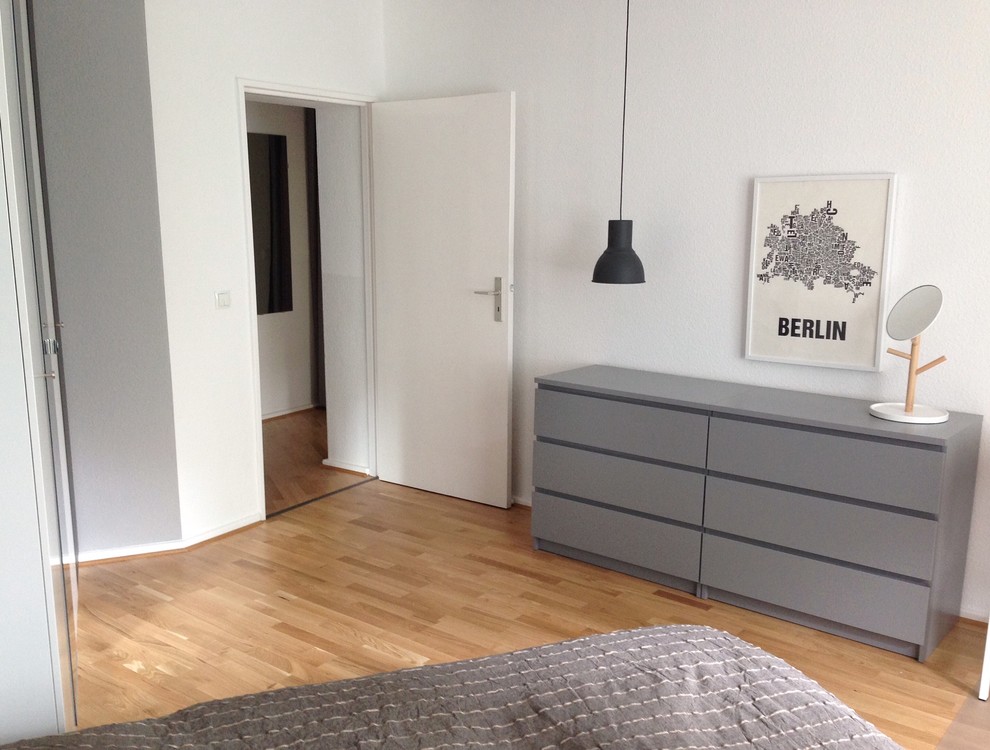 Réalisation d'une petite chambre parentale nordique avec un mur gris et un sol en bois brun.