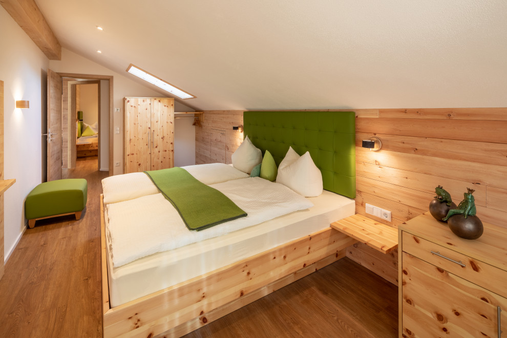 Mittelgroßes Landhaus Hauptschlafzimmer mit weißer Wandfarbe, braunem Holzboden und braunem Boden in Sonstige
