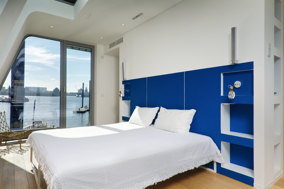 Esempio di una camera matrimoniale costiera di medie dimensioni con pareti blu, pavimento in legno massello medio e nessun camino
