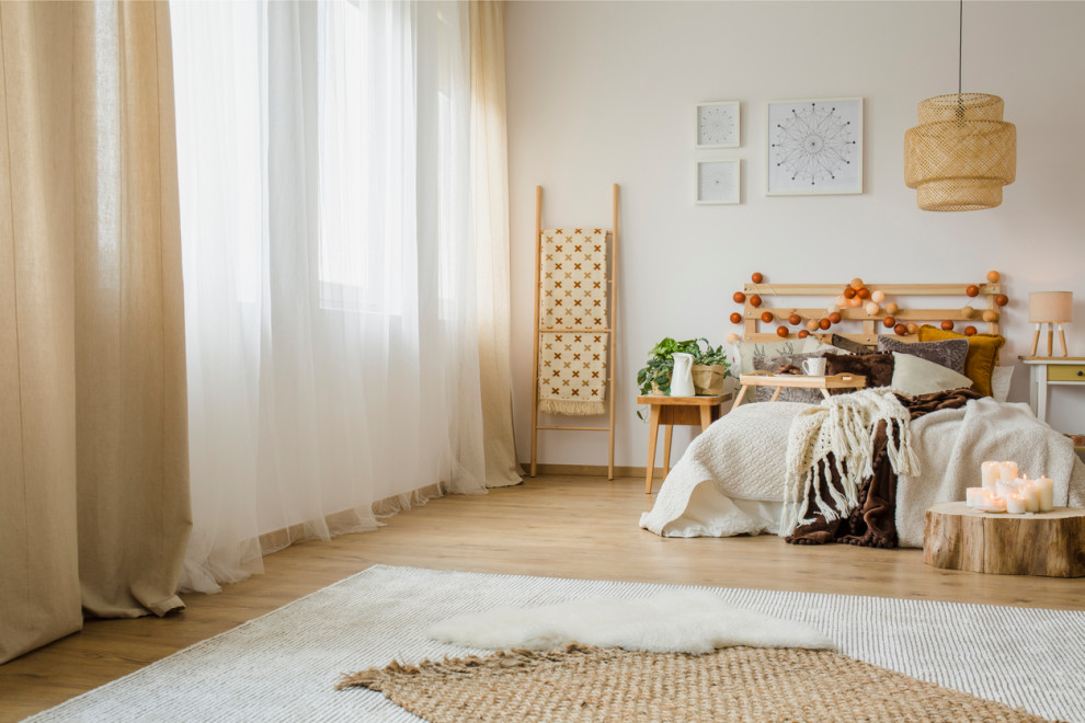 Skandinavisches Schlafzimmer mit beiger Wandfarbe, braunem Holzboden, braunem Boden und Tapetenwänden