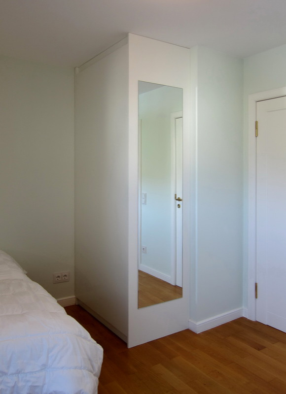 Cette image montre une petite chambre d'amis design avec un mur vert, un sol en bois brun et un sol marron.