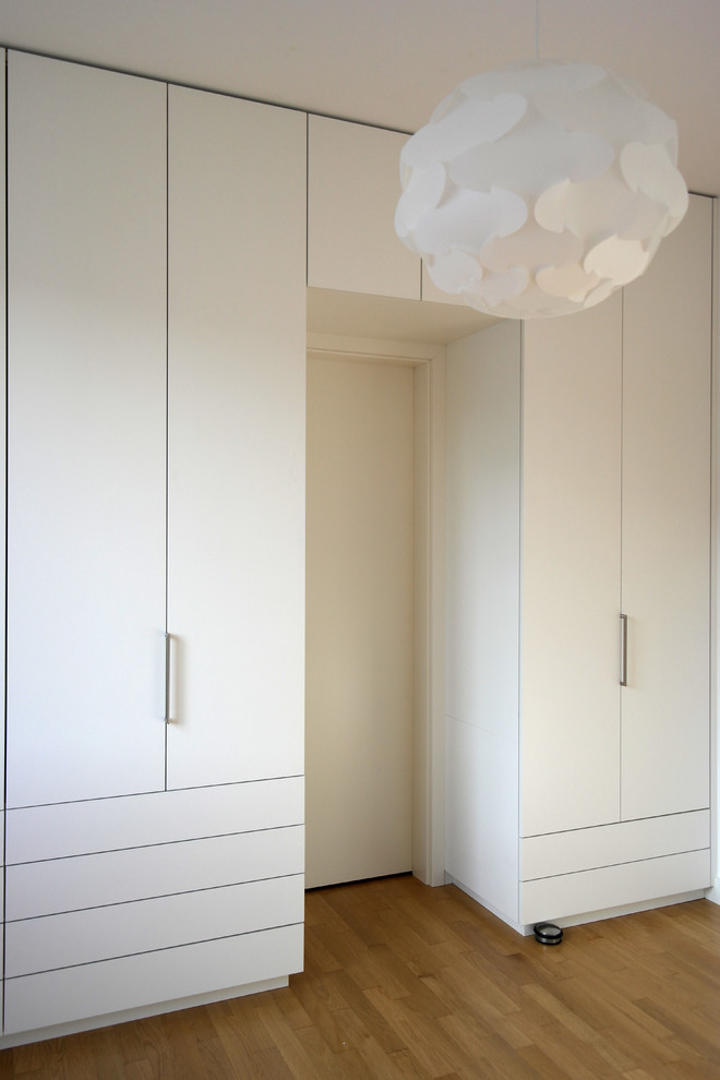 Diseño de dormitorio moderno extra grande con suelo de madera en tonos medios, paredes blancas y suelo marrón