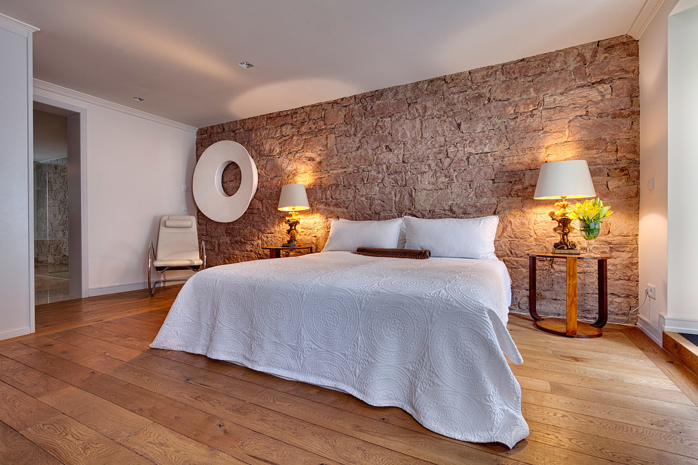 Immagine di una grande camera da letto design con pareti bianche, pavimento in legno massello medio e nessun camino