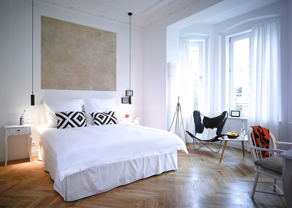 Imagen de dormitorio principal contemporáneo grande sin chimenea con paredes blancas y suelo de madera en tonos medios