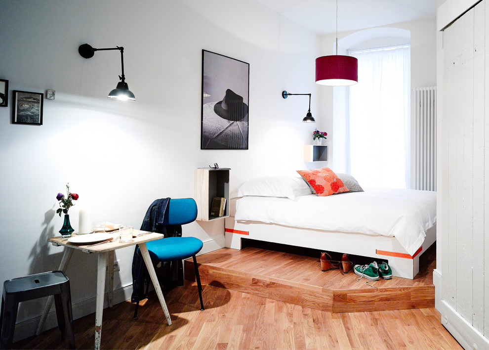 Kleines Modernes Hauptschlafzimmer ohne Kamin mit weißer Wandfarbe und braunem Holzboden in Berlin