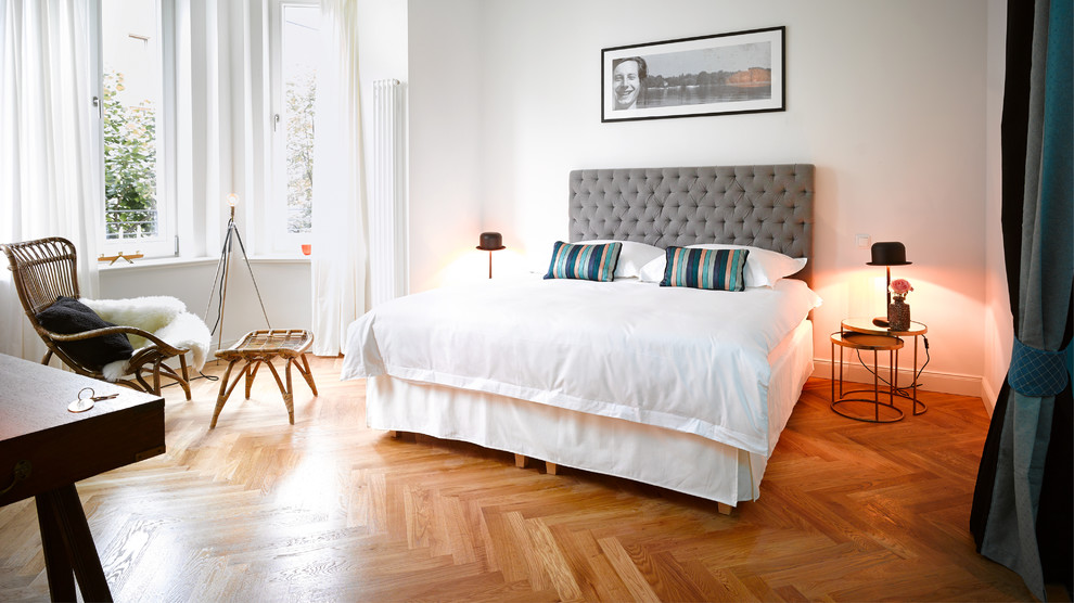 This is an example of a large contemporary master bedroom in Berlin with white walls, medium hardwood flooring and no fireplace.
