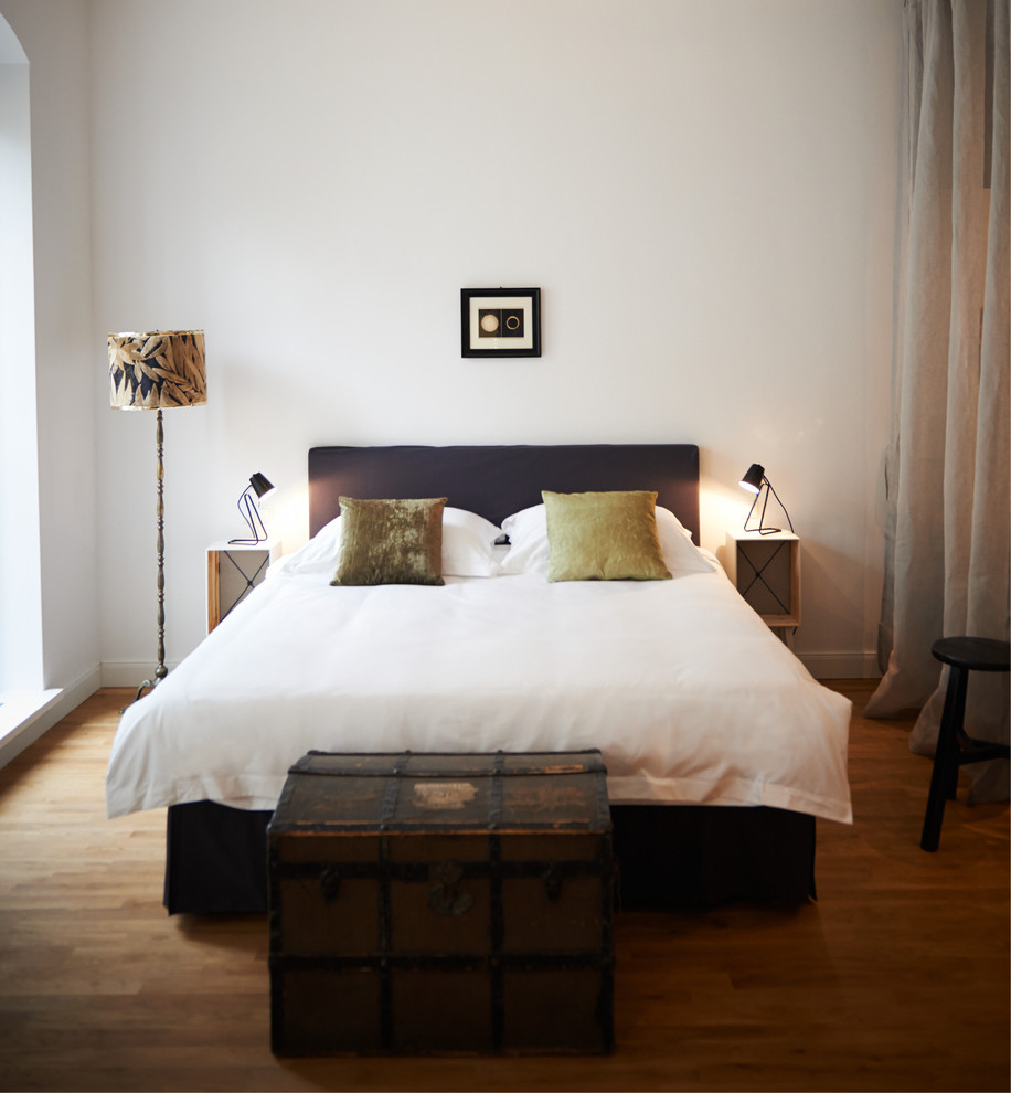 Mittelgroßes Modernes Schlafzimmer ohne Kamin mit weißer Wandfarbe und braunem Holzboden in Berlin