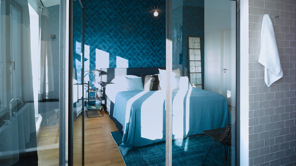 Ejemplo de dormitorio contemporáneo de tamaño medio sin chimenea con paredes azules y suelo de madera en tonos medios