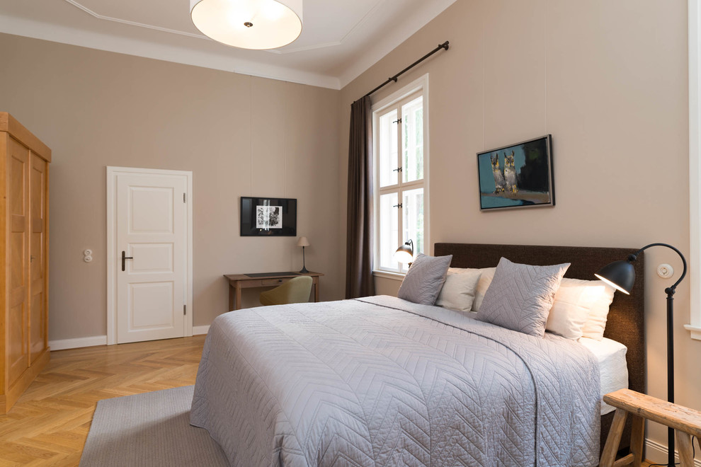 Modelo de dormitorio principal vintage grande sin chimenea con paredes beige, suelo de madera en tonos medios y suelo marrón