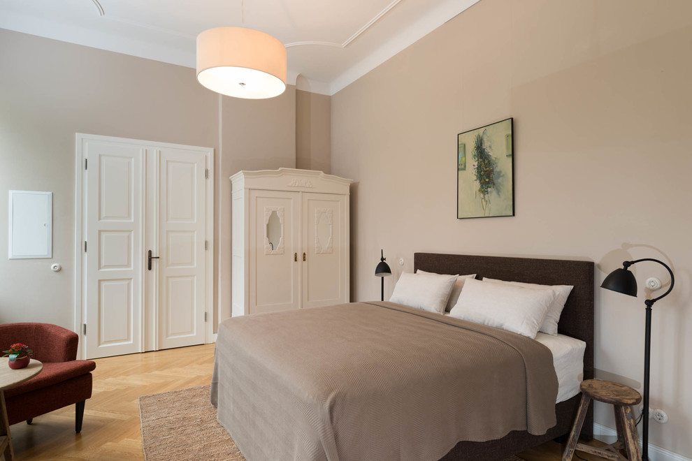 Großes Landhausstil Hauptschlafzimmer ohne Kamin mit beiger Wandfarbe, braunem Holzboden und braunem Boden in Berlin