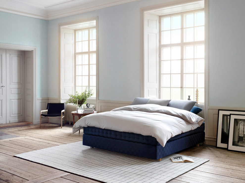 Immagine di una grande camera matrimoniale nordica con pareti blu, pavimento in legno massello medio e pavimento marrone