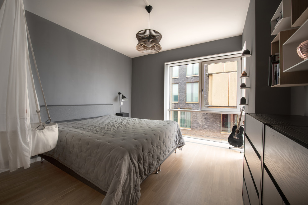 Imagen de dormitorio principal nórdico de tamaño medio con paredes grises y suelo de madera en tonos medios