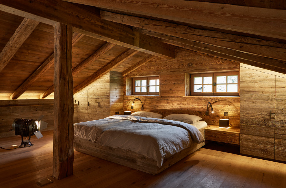 Großes Uriges Hauptschlafzimmer ohne Kamin mit brauner Wandfarbe, gebeiztem Holzboden und braunem Boden in München