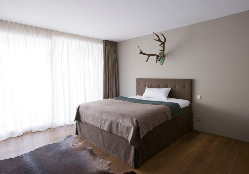 На фото: хозяйская спальня среднего размера в современном стиле с коричневыми стенами и темным паркетным полом без камина с