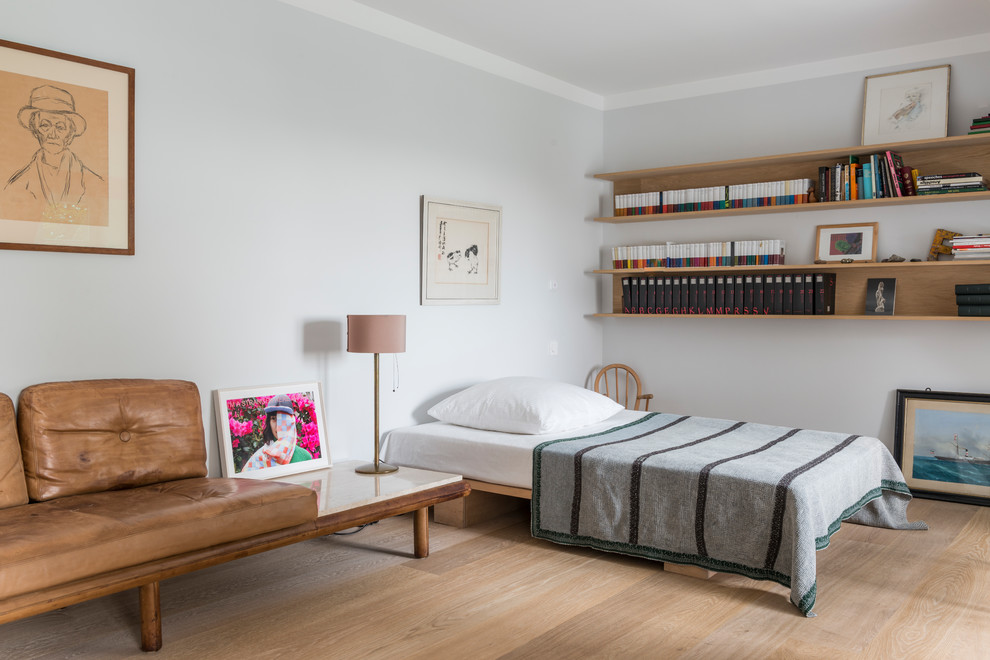 Ejemplo de habitación de invitados actual grande sin chimenea con paredes blancas, suelo de madera clara y suelo beige