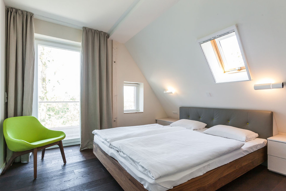 На фото: спальня среднего размера на мансарде в современном стиле с белыми стенами и темным паркетным полом без камина с