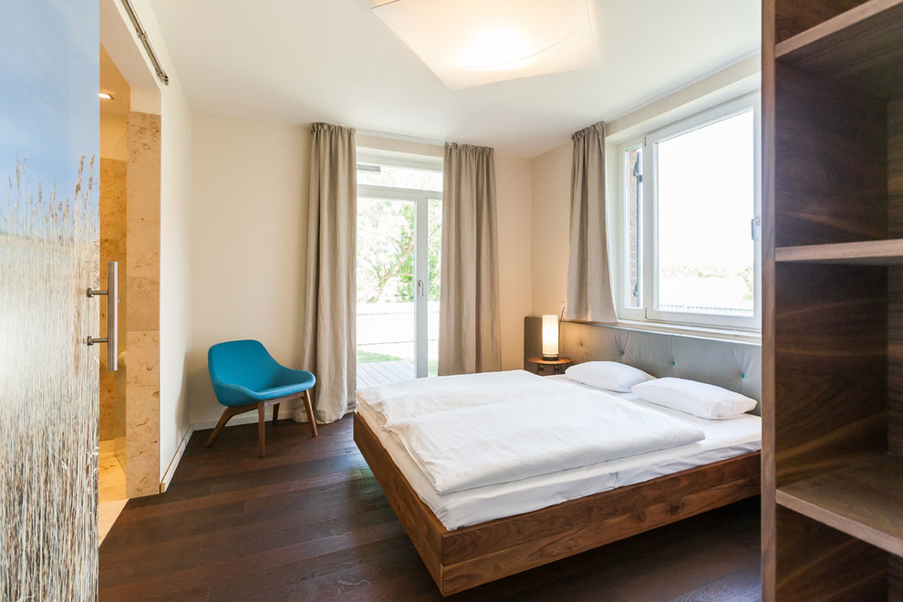 Mittelgroßes Modernes Hauptschlafzimmer ohne Kamin mit weißer Wandfarbe und dunklem Holzboden in Berlin