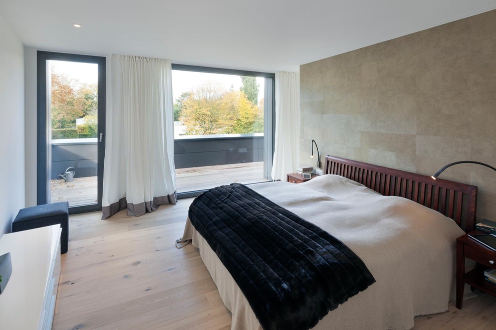 Diseño de dormitorio principal actual de tamaño medio sin chimenea con paredes beige y suelo de madera clara