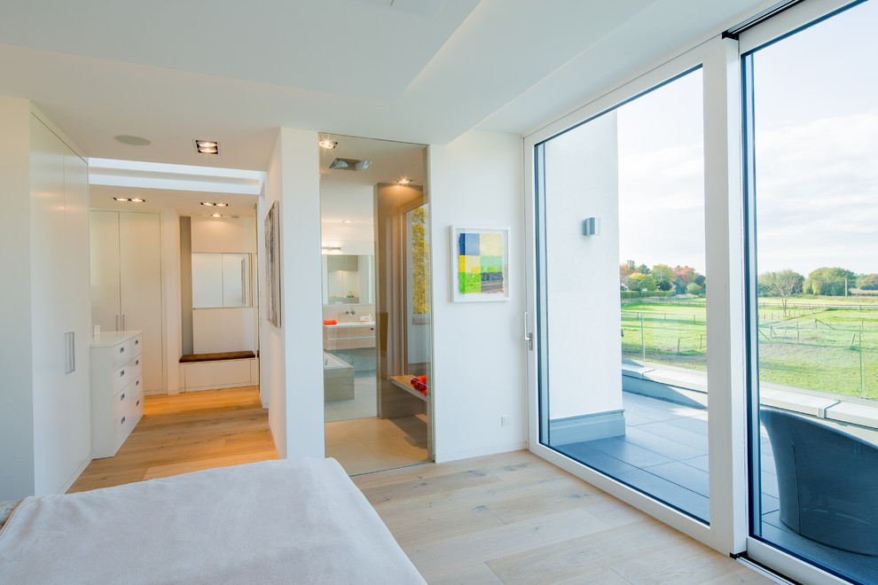 Mittelgroßes Modernes Hauptschlafzimmer ohne Kamin mit beigem Boden, weißer Wandfarbe und braunem Holzboden in Düsseldorf