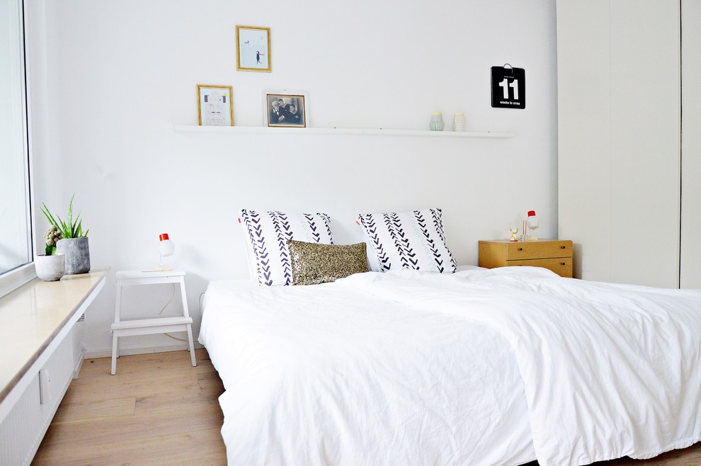 На фото: хозяйская спальня среднего размера в скандинавском стиле с белыми стенами и светлым паркетным полом без камина с