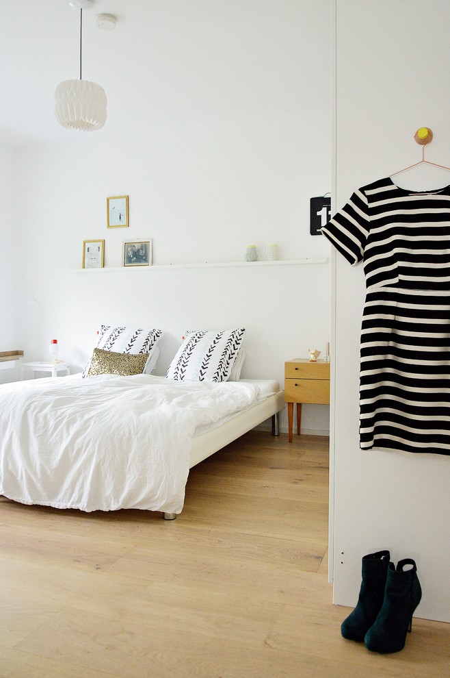 Modelo de dormitorio nórdico de tamaño medio sin chimenea con paredes blancas y suelo de madera en tonos medios