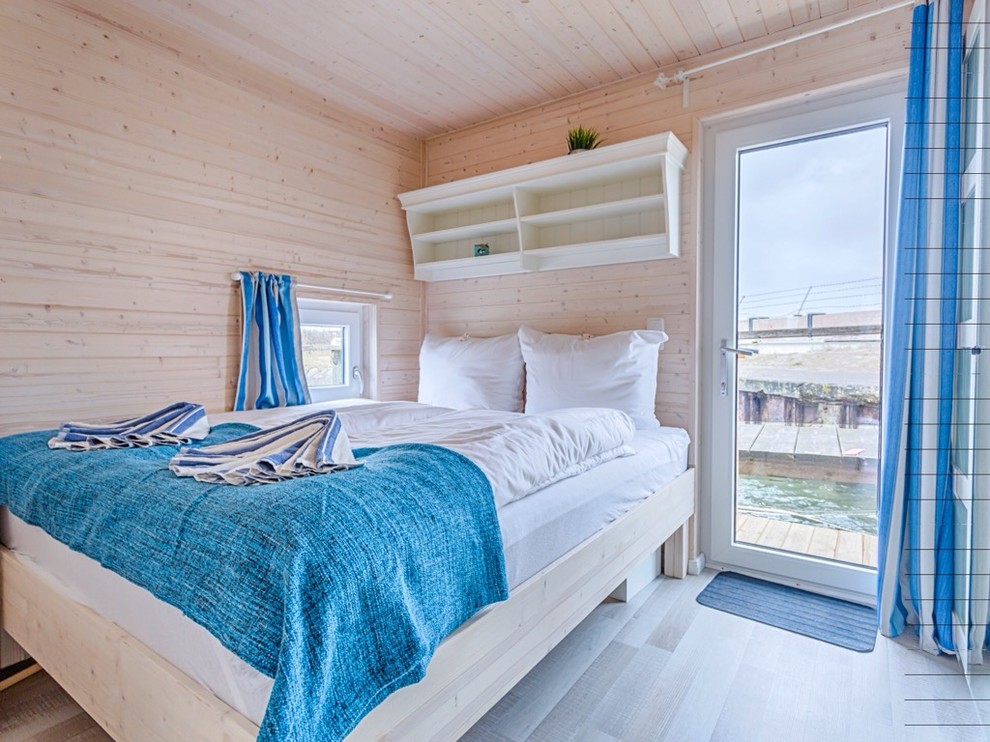 Bedroom - coastal master laminate floor and gray floor bedroom idea in Hamburg with white walls
