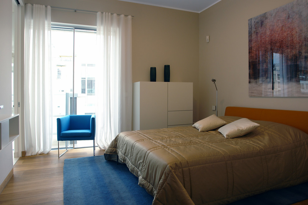 Modernes Schlafzimmer ohne Kamin mit beiger Wandfarbe und braunem Holzboden in Berlin