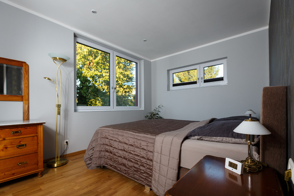 Großes Modernes Hauptschlafzimmer mit grauer Wandfarbe und dunklem Holzboden in Sonstige