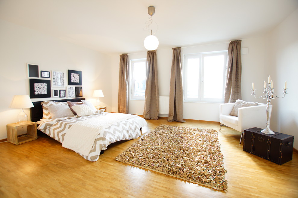 他の地域にある巨大なコンテンポラリースタイルのおしゃれな主寝室 (白い壁、無垢フローリング、暖炉なし)