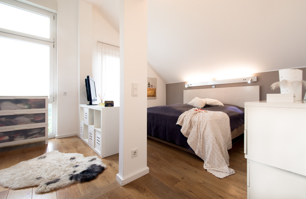 Modelo de dormitorio televisión contemporáneo sin chimenea con paredes grises y suelo de madera en tonos medios