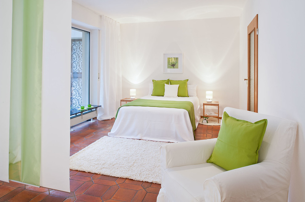 Diseño de dormitorio principal actual de tamaño medio sin chimenea con paredes blancas y suelo de baldosas de terracota