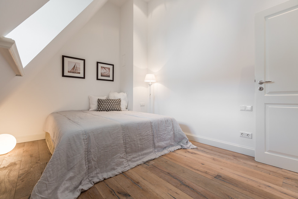 Mittelgroßes Nordisches Schlafzimmer im Dachboden ohne Kamin mit weißer Wandfarbe und braunem Holzboden in Sonstige