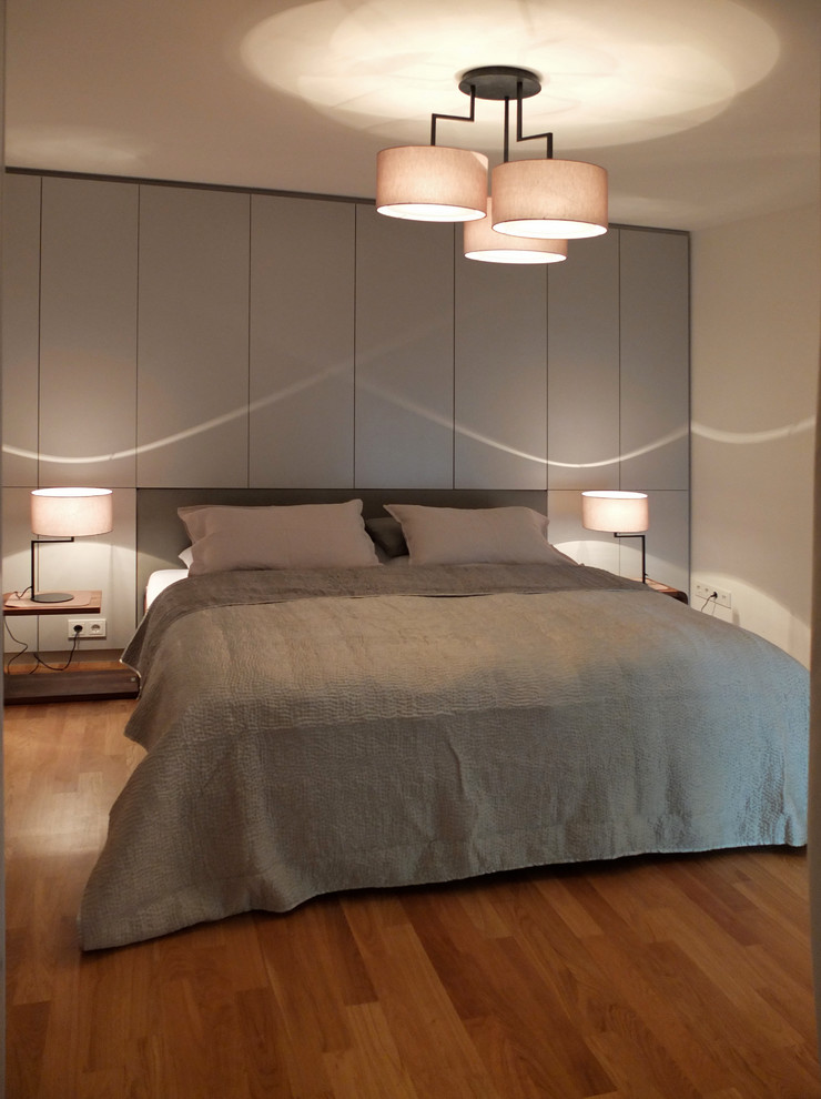 Example of a trendy master medium tone wood floor bedroom design in Berlin with beige walls and no fireplace