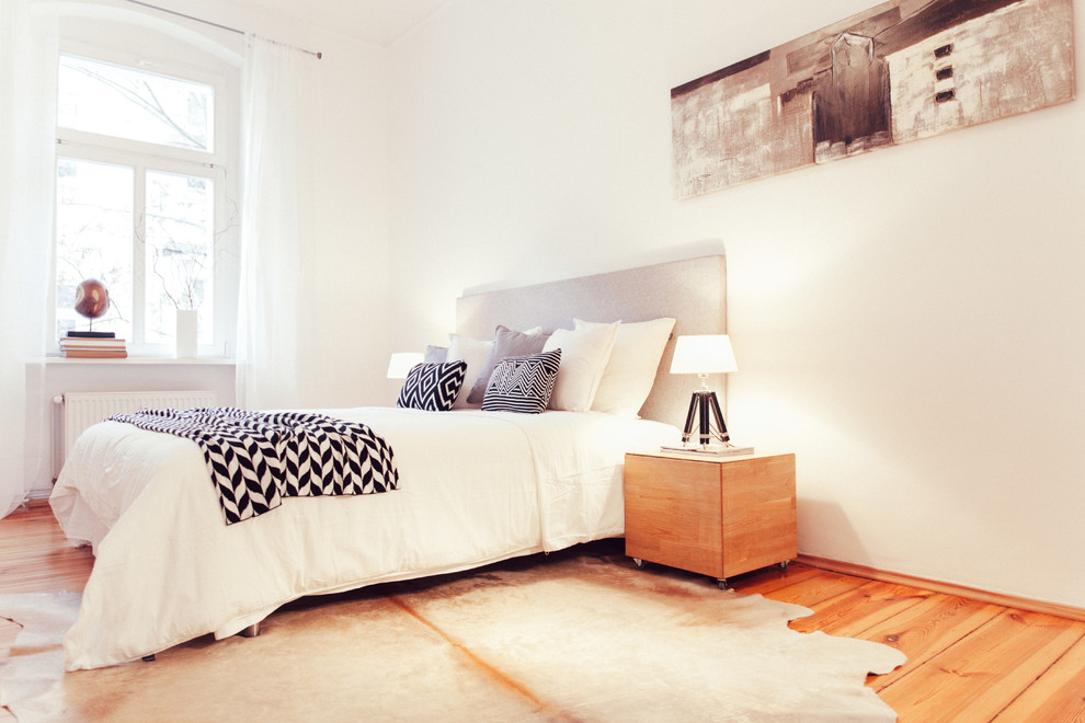 Mittelgroßes Skandinavisches Hauptschlafzimmer ohne Kamin mit weißer Wandfarbe und hellem Holzboden in Berlin