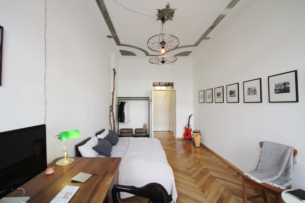 Medium sized industrial master bedroom in Berlin with white walls, medium hardwood flooring and no fireplace.