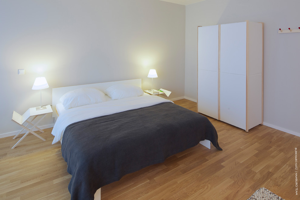 Großes Modernes Schlafzimmer ohne Kamin mit grauer Wandfarbe und braunem Holzboden in Hamburg