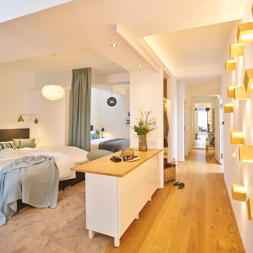 Modelo de dormitorio tipo loft contemporáneo extra grande con paredes blancas, suelo de madera en tonos medios y suelo beige