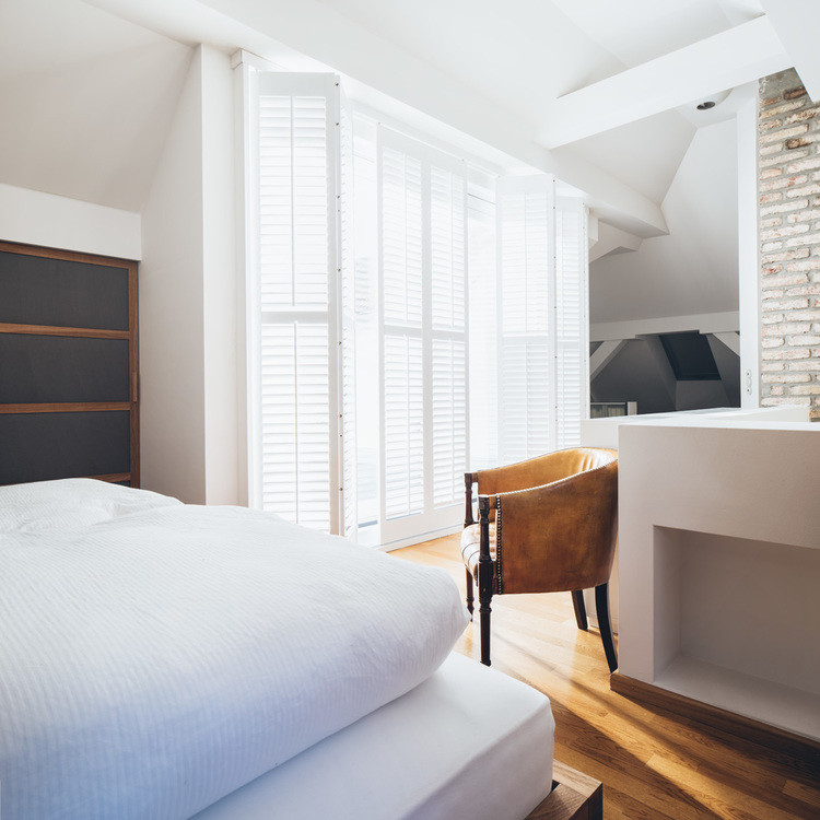 Modernes Schlafzimmer ohne Kamin mit weißer Wandfarbe und braunem Holzboden in München