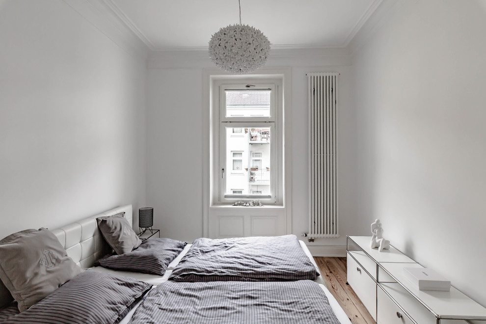 Idéer för nordiska sovrum, med vita väggar, mellanmörkt trägolv och brunt golv