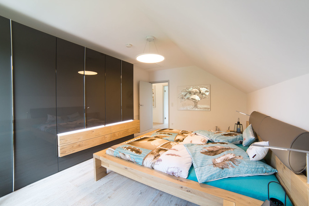 Ejemplo de dormitorio principal actual de tamaño medio sin chimenea con paredes blancas, suelo de madera clara y suelo beige