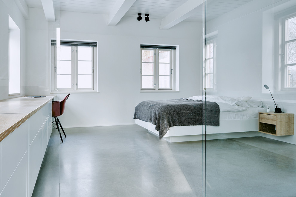 Bild på ett stort funkis sovrum, med vita väggar och betonggolv