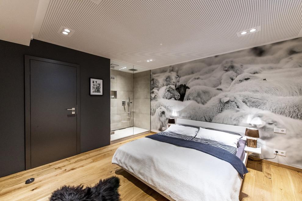 Cette image montre une chambre d'amis urbaine de taille moyenne avec un mur noir, un sol en bois brun et un sol marron.