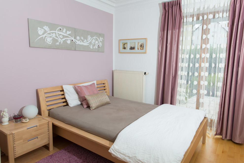 Landhausstil Schlafzimmer mit braunem Holzboden und lila Wandfarbe in München