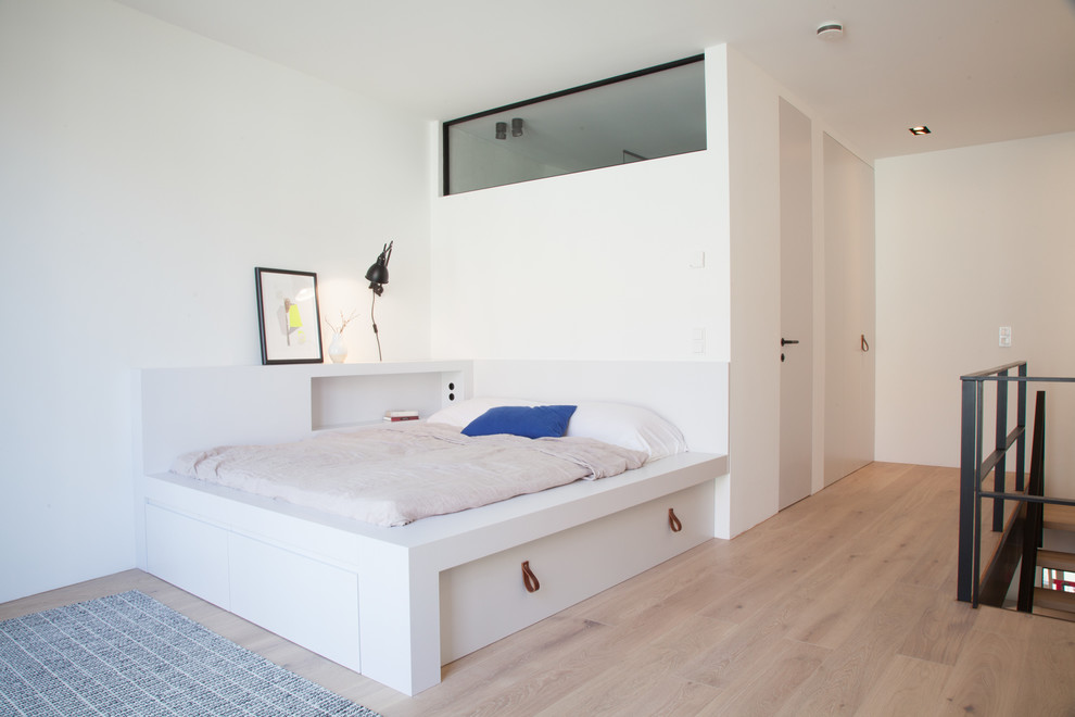 Immagine di una camera da letto stile loft design di medie dimensioni con pareti bianche, pavimento in legno massello medio, pavimento marrone e nessun camino