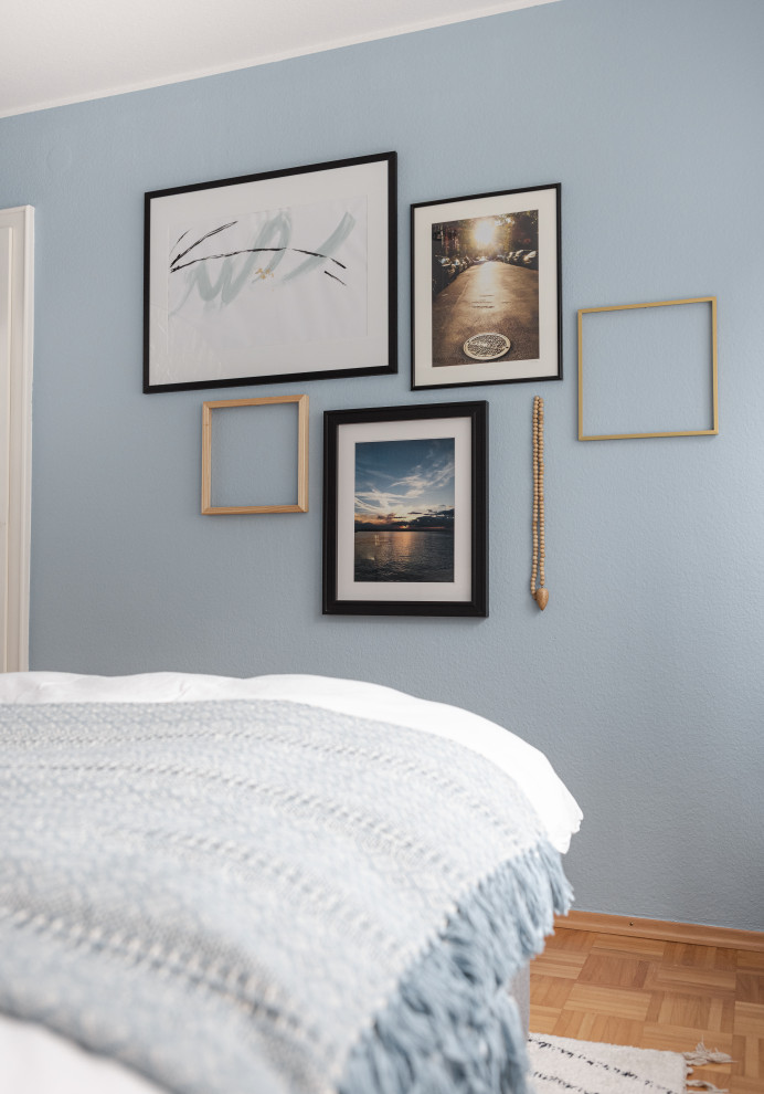 Inspiration pour une petite chambre d'amis design avec un mur bleu, un sol en bois brun et du papier peint.