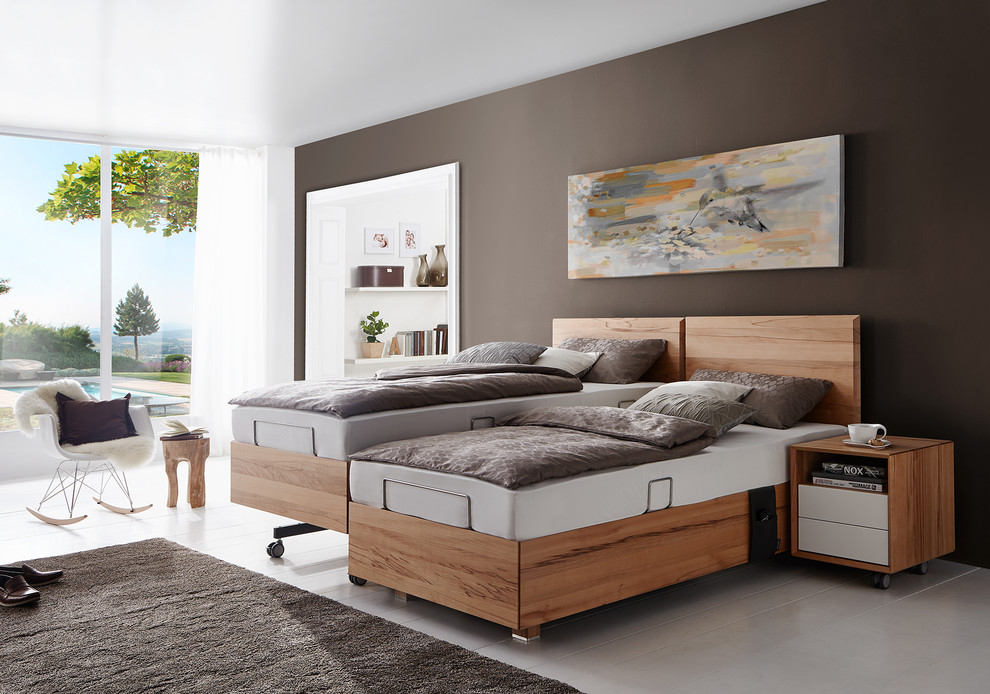 Imagen de dormitorio principal actual de tamaño medio sin chimenea con paredes marrones, suelo de madera clara, suelo blanco y marco de chimenea de madera